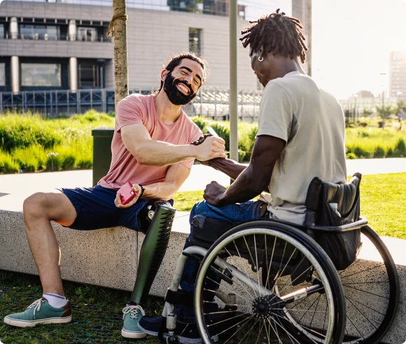 person sitting on bench shaking hands with person in wheelchair